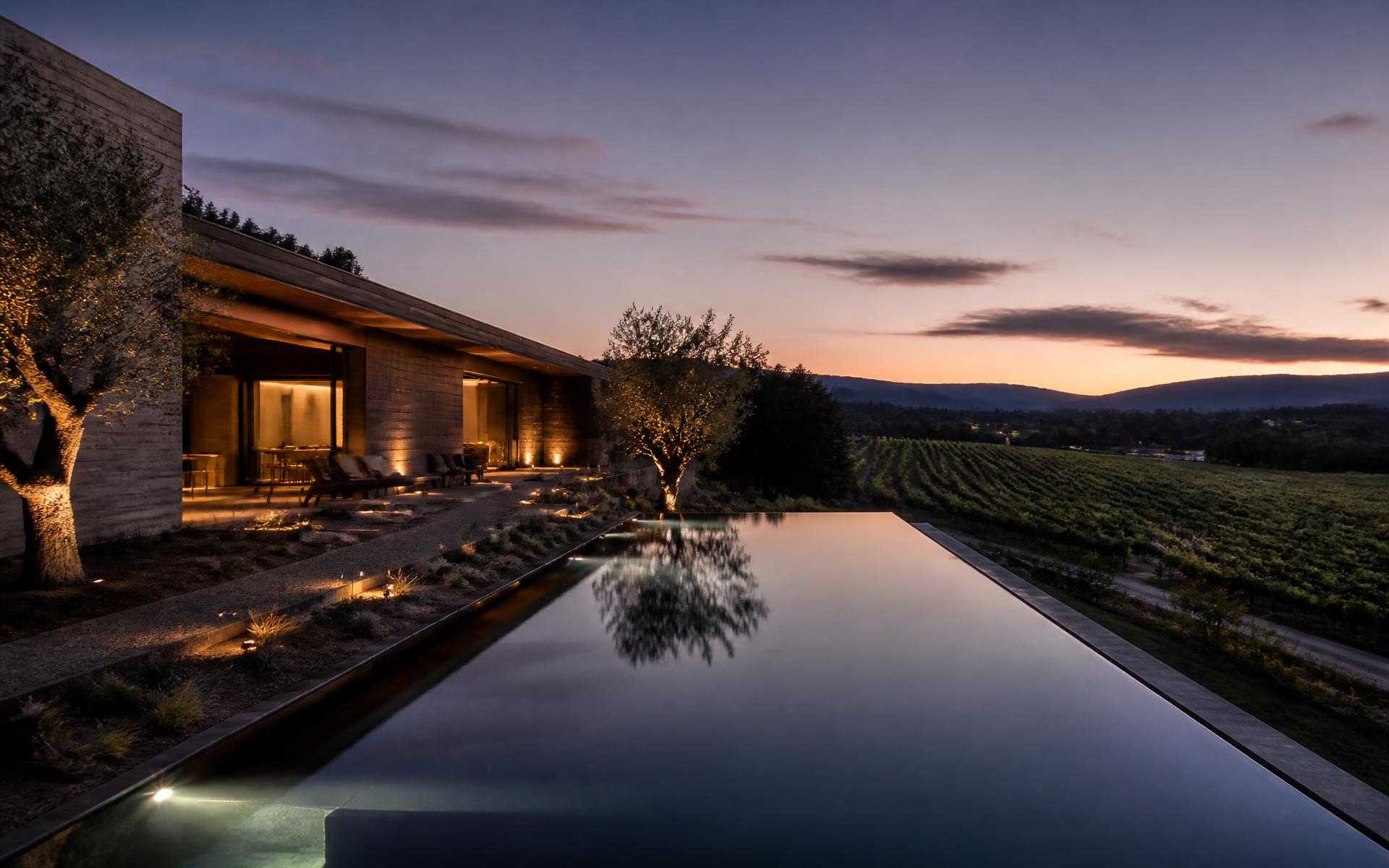 Vineyard estate exterior at twilight with infinity pool and olive trees